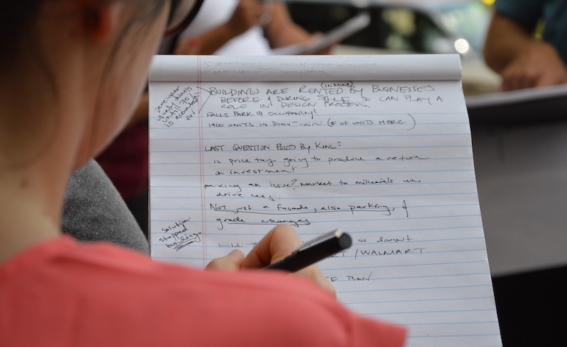 over-the-shoulder shot of an individual working on a clip board. Written on the page are critical questions related to housing